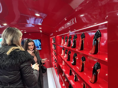 Two women check out the Good Girl shoe bottle collection inside Carolina Herrera's custom promotional Airstream trailer