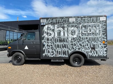An American ambulance or side step van for Vercel, wrapped in matte black vinyl for a live promotion/activation.