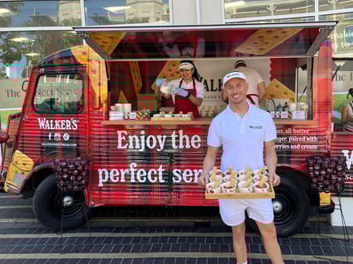 A male influencer stands ready with free shortbread samples in front of a branded tartan H-Van.
