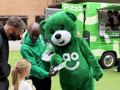 A character poses with a child for the AO Bear's Pizza promotional sampling food and beverage campaign.