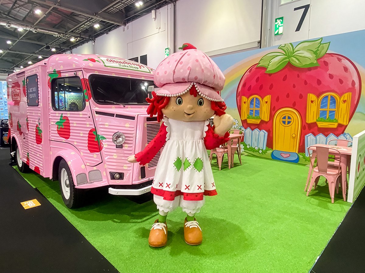 A pink classic H-Van and Strawberry Shortcake at an exhibition.