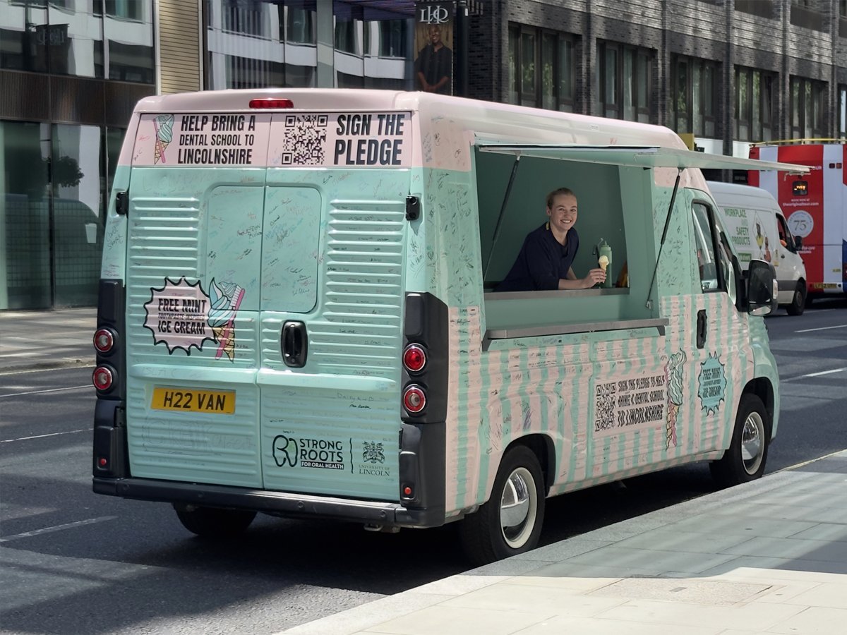 A girl poses in a modern Citroen H Van Type H Relay - with a branded wrap idea for people to sign as part of a petition for the Strong Roots University of Lincoln campaign.