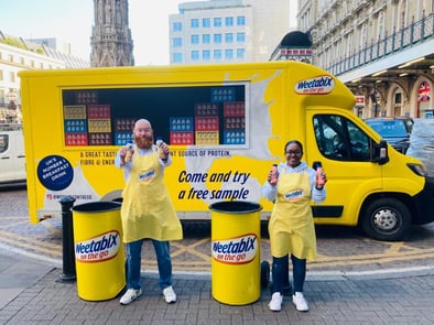 Two staff members stand near the Weetabix sampling van