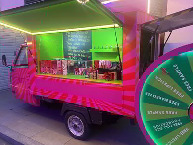 The MAC Cosmetics Piaggio Ape with lights, products, and spin the wheel game.