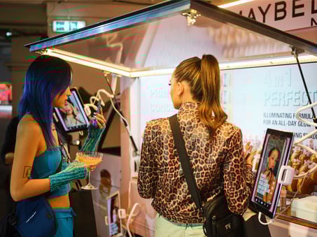 Influencers pose by the Maybelline make-up event, featuring  LED lights and digital touchscreens.