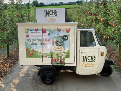 The Inch's Cider Piaggio Ape in an orchard, ready to for guests to enjoy free drinks.