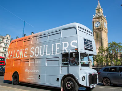 The Malone Souliers Routemaster branded bus in London, driving past Big Ben.
