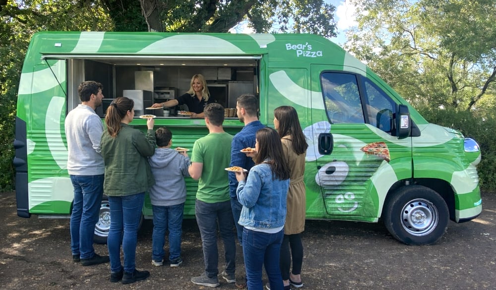 A crowd of hungry guests around AO Bears Pizza sampling Van