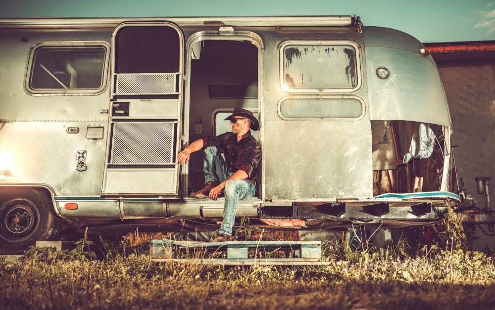 A cowboy poses in the door of a vintage Airstream trailer.