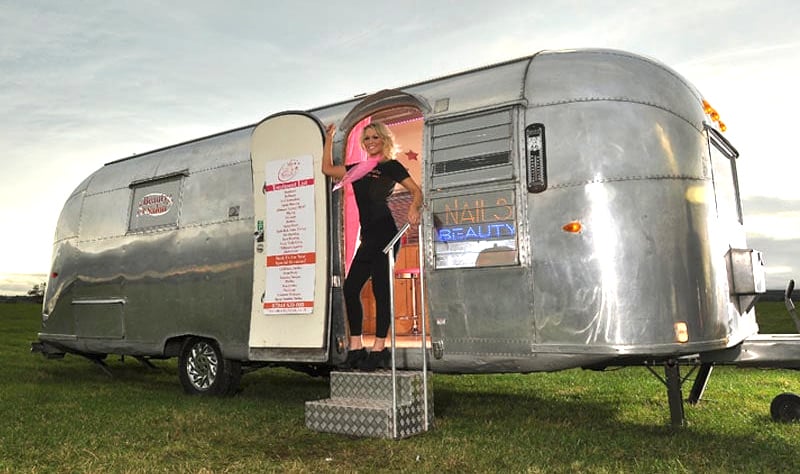 A classic Airstream for Nail & Beauty, with a young blonde woman posing.