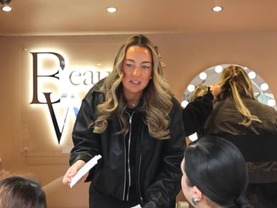 A staff member hands out vouchers, with the Beauty Works logo behind while a guest enjoys haircare.