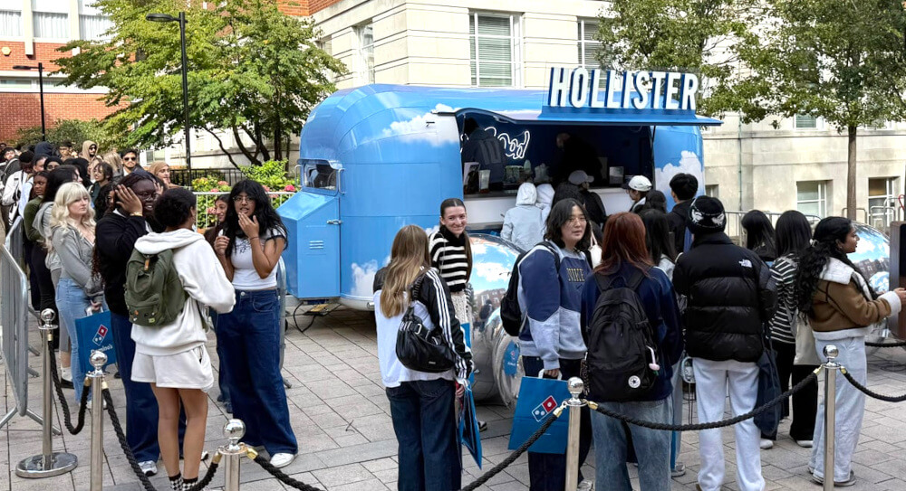 A crowd with Hollister's blue sky Airstream at a live event in the city of London.