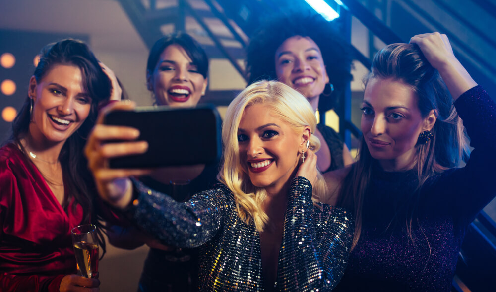 A group of influencers pose with a phone camera at a special brand activation event.