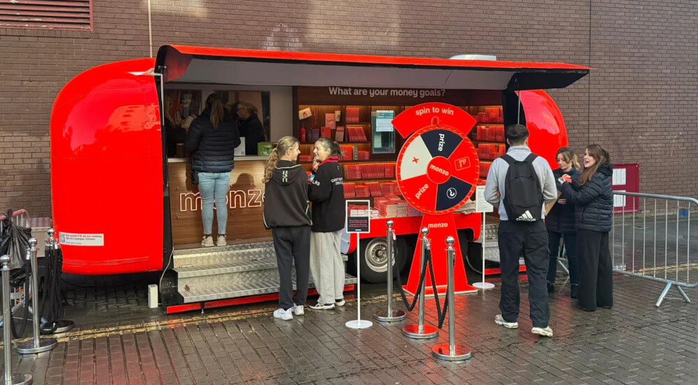 A custom Airstream interior by Monzo, with a wheel game and small crowd.