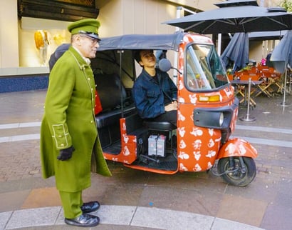 An influencer and concierge stand with the Born to Stand Out campaign tuk tuk.