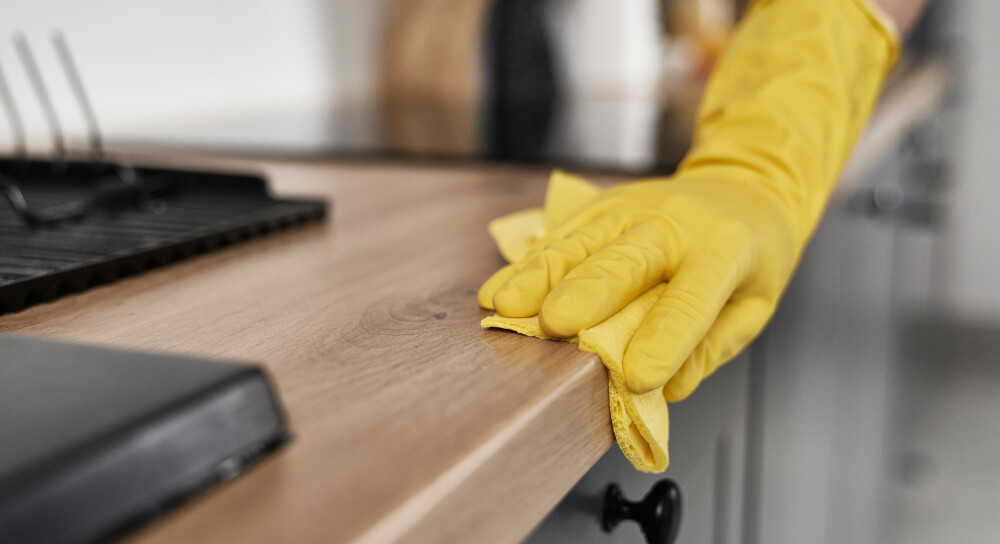 A staff member meets the challenge of a food sampling campaign by cleaning the kitchen space with rubber gloves.