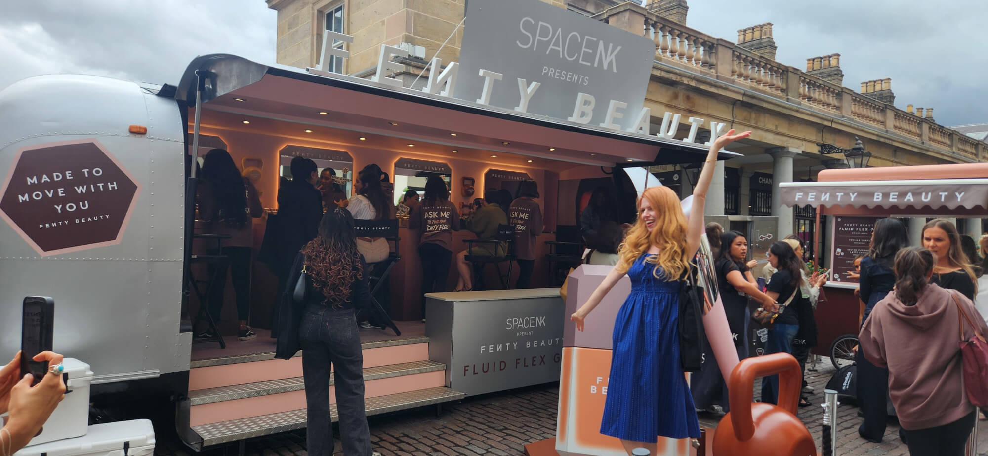 A woman poses with a crowd for Fenty Beauty's promotional marketing Airstream.