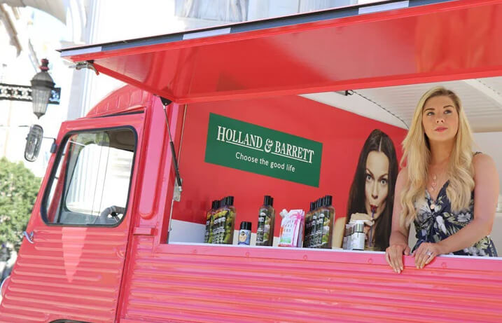 A young woman waits to drive customer engagement for Holland & Barrett as part of a pop-up experience.