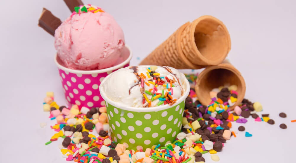 Ice cream samples with cones and coloured tubs, surrounded by sprinkles