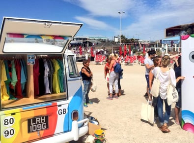 Beachgoers engage with a promotional VW camper van.