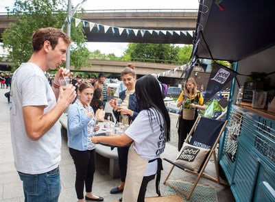 In-action campaign image of staff handing out free drinks to a crowd.