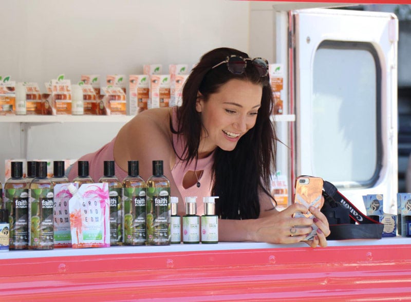 A woman at Holland & Barrett shares the experiential event online, with wellness bottles in shot.