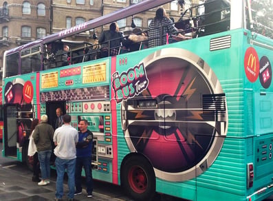 A crowd of influencers outside and on the top deck of the promotional tour bus for McDonald's.