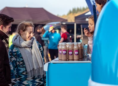 Guests look at free bottled samples on a blue Land Rover Defender