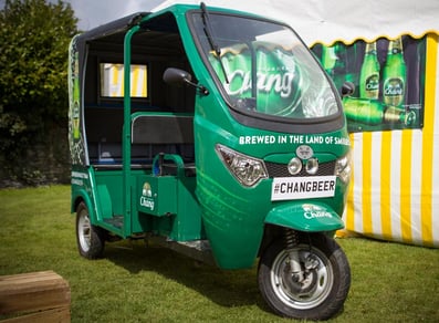 The front and side of the green Chang Beer promotional tuk tuk at a festival