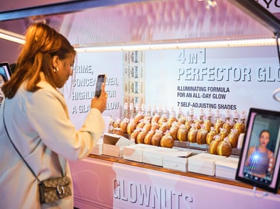 A woman takes a picture of the custom L'Oreal and Maybelline Piaggio Ape