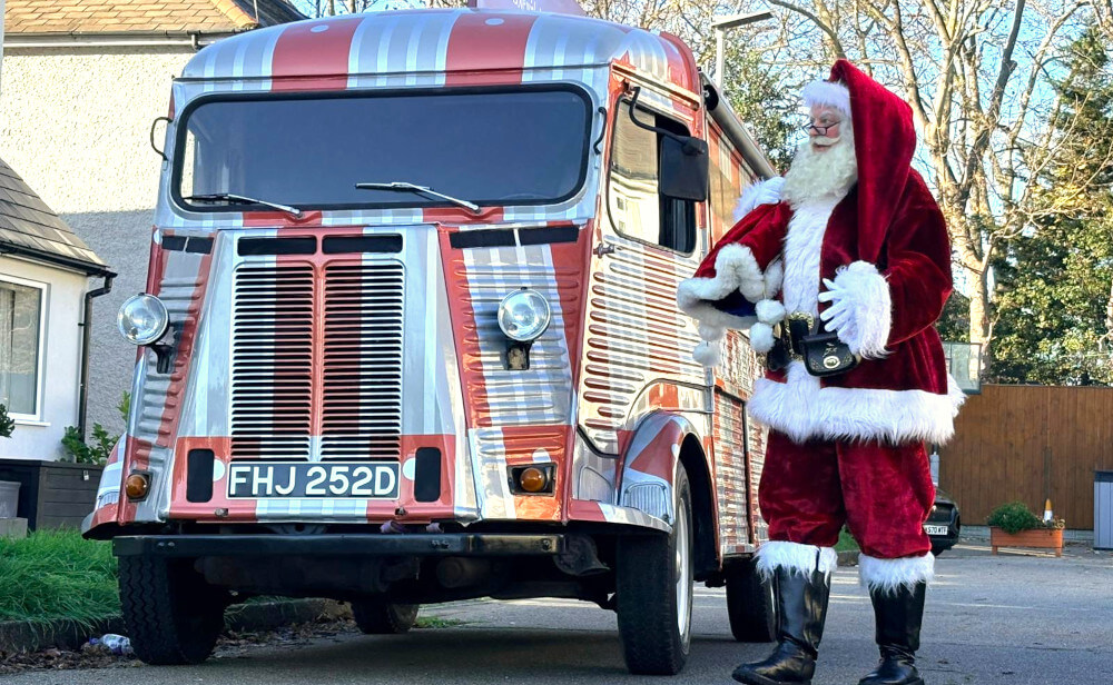 Santa with Naturium's red and silver Citroen H Van, a vintage model.
