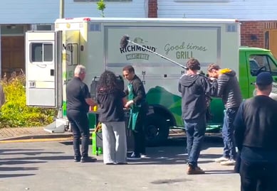 A film crew and Joe Swash in front of the Richmond American ambulance for a brand activation or experiential marketing campaign.