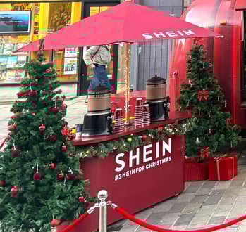 A red event counter, with hot chocolate machines and Christmas trees for SHEIN's brand campaign.