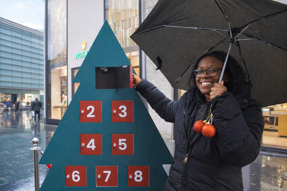 A woman holding an umbrella poses with a Christmas game as part of a city brand activation, for SHEIN and in association with Promohire.