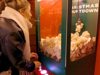 A young woman has fun with a crane or claw machine.