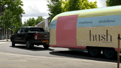 blue yellow pink Hush vintage Airstream towed by support truck