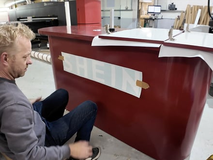 Promohire design and build staff, constructing one of SHEIN's event props - a red counter for a Christmas pop-up.