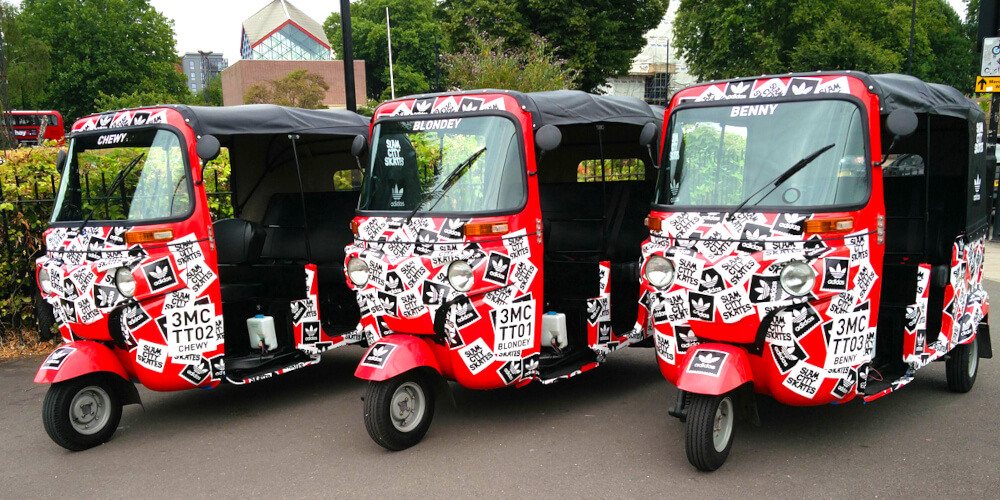 3 red hire tuk tuks in a row, branded for Slam City
