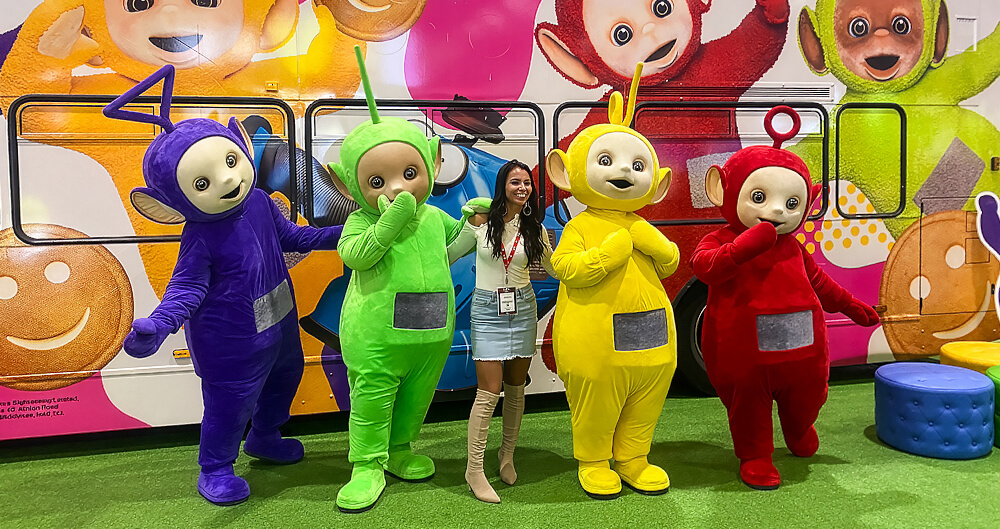 The Teletubbies standing with a guest and their brand campaign bus.