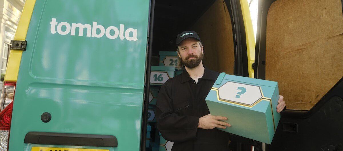 A staff member holds a 'deal or no deal' box for Tombola's prize draw gamification element.