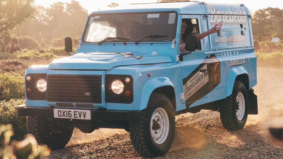 A promotional Land Rover Defender on the road.