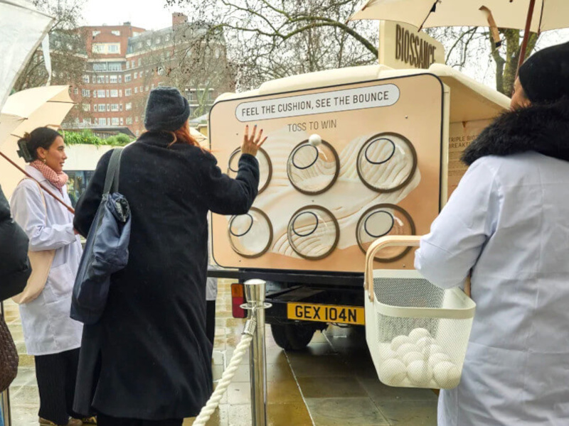 A group of women play with the gamification element on the Biossance promotional milk float.