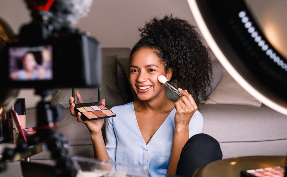 A female brand influencer poses with make-up and ring light for a social media video.