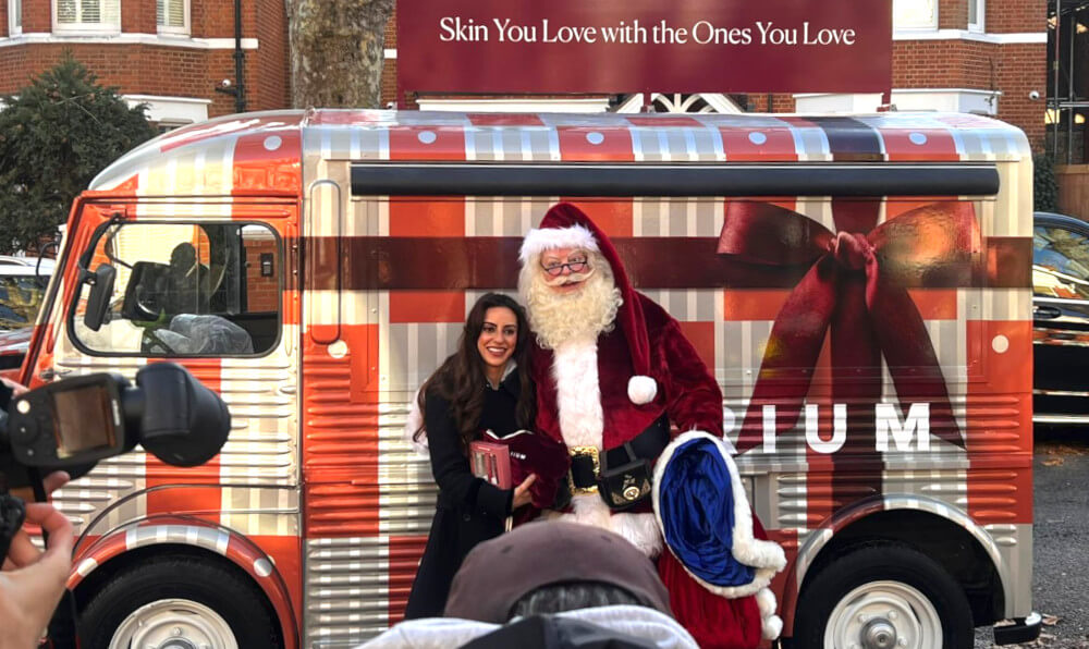 Santa and a guest in front of cameras at Naturium's beauty and skincare pop-up event.