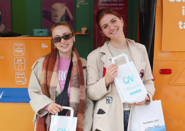Two young students enjoy gift bags during a live freshers' week campaign experience.