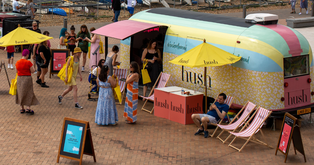 Hush vintage Airstream activation blue yellow green red counters yellow parasols branded chalkboards seaside